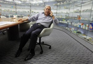 Hamied, chairman and MD of Indian generic drugmaker Cipla, speaks on mobile phone in front of cabinets containing company's products before interview in Mumbai