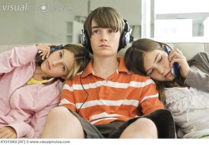 Two girls talking on mobile phones with a boy listening to headphones