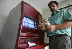 A man counts money after withdrawing it from an ATM in Jammu